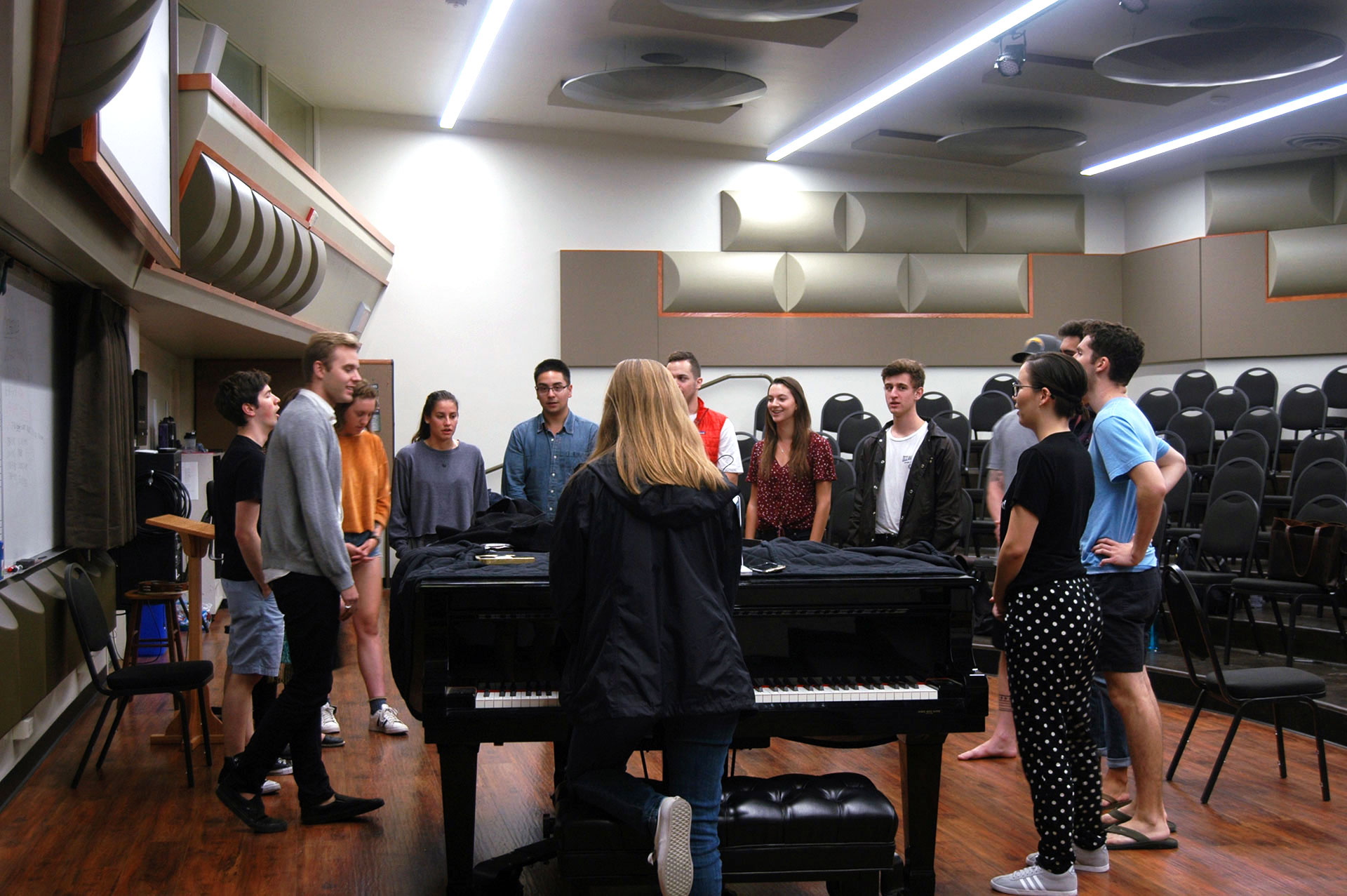 October 8, 2017 | San Luis Obispo, CA | Music sophomore Molly Gooch (center) proceeds to
conduct the rehearsal, playing four notes in the lower register of the piano. She’s reminding the
basses how their opening part sounds so that they may begin singing “Surfer Girl” by The
Beach Boys. “Surfer Girl” is one tune in a set of almost ten songs that the group will perform at
their winter concert (and subsequent gigs.)