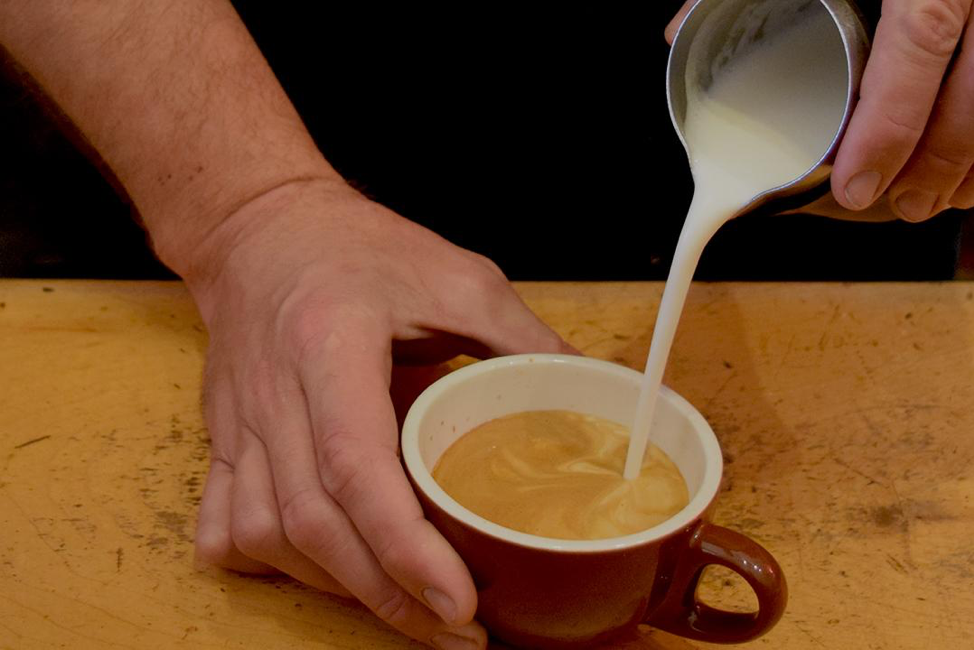 Chris Burd begins pouring steamed soy milk into espresso at Linnea’s Cafe on Monday, October 22.