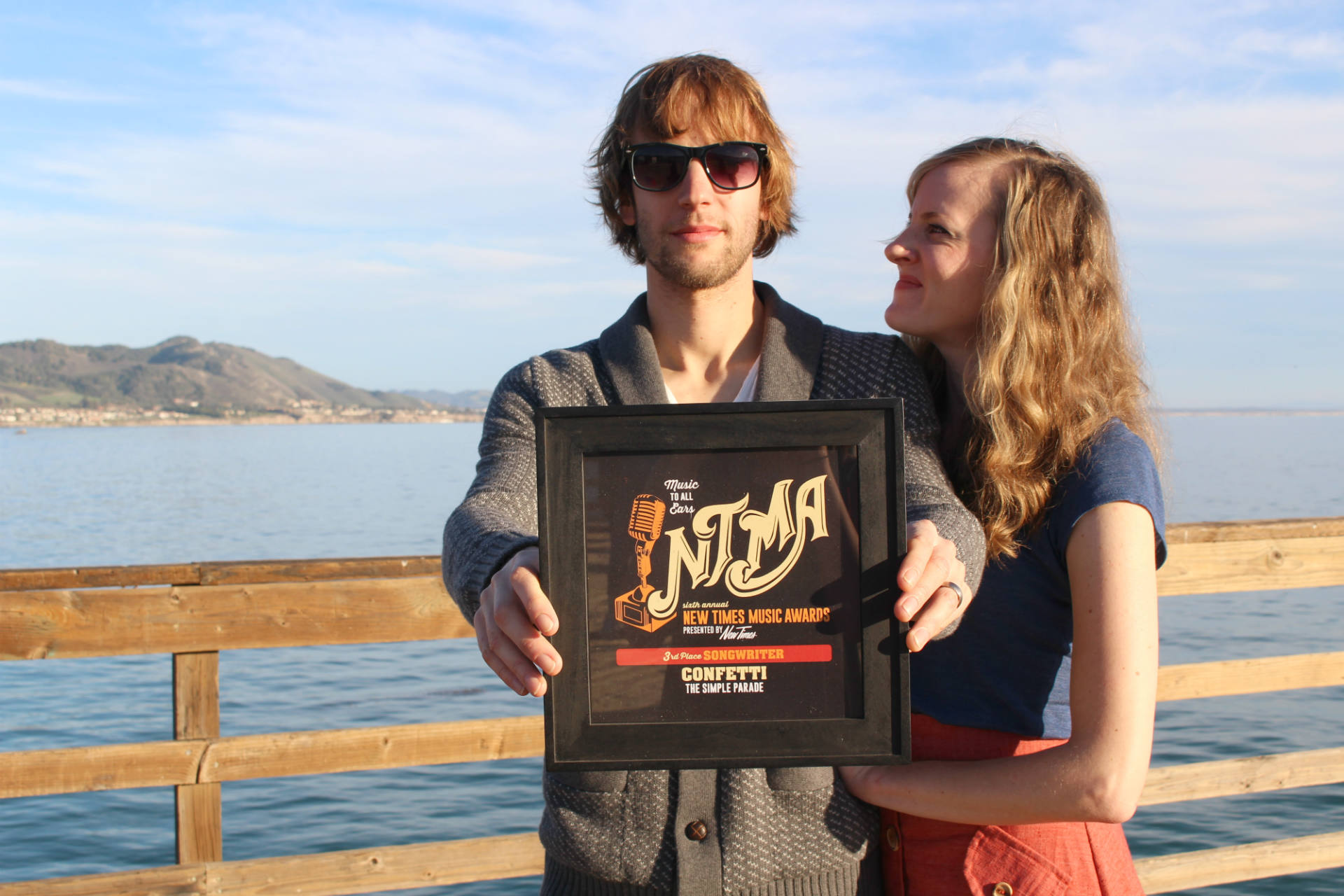 <b>An award well-deserved.</b>
Kayla Hooper beams at husband Justin as he holds up the third place songwriter award from New Times for the original song 'Confetti' in Avila Beach, California. 'The Simple Parade has a lot of meanings, but primarily it comes from the first song we wrote as a single called ‘Confetti’ that is meant to convey the message of enjoying the simple thrills of your parade.' 
