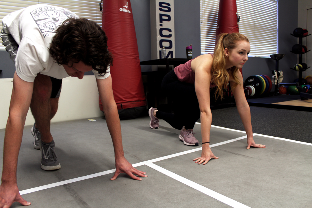 Tommy Sidebottom, left, and Emily Campbell, right, are two of Dahmen’s clients. He has them begin with several warm-up stretches and a few rounds of sprints in the indoor track. Photo Credit: Taylor Keefer