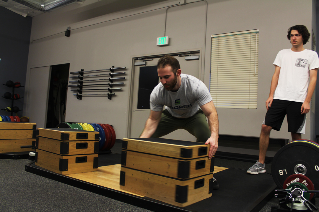Both Sidebottom and Campbell have been working with Dahmen for several months. One of the biggest struggles Dahmen has had to deal with in his line of work revolves around finding new clientele, and keeping them for long periods of time. Dahmen is pictured setting up wooden boxes for a plyometric exercise that trains muscles to increase power. Photo Credit: Taylor Keefer